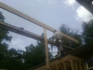 Carpenter setting a ridge beam over a new addition frame — Ice Dam Removal by Roofing Brothers in Hanley Falls