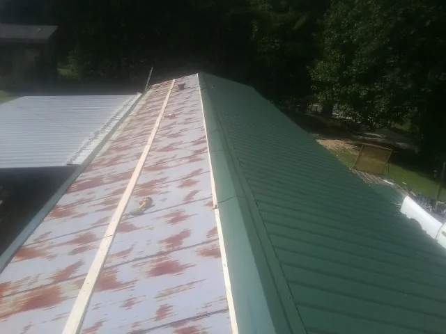 Old rusted panels beside newly installed green metal roofing — Wind Damage Roof Repair by Roofing Brothers in Hanley Falls
