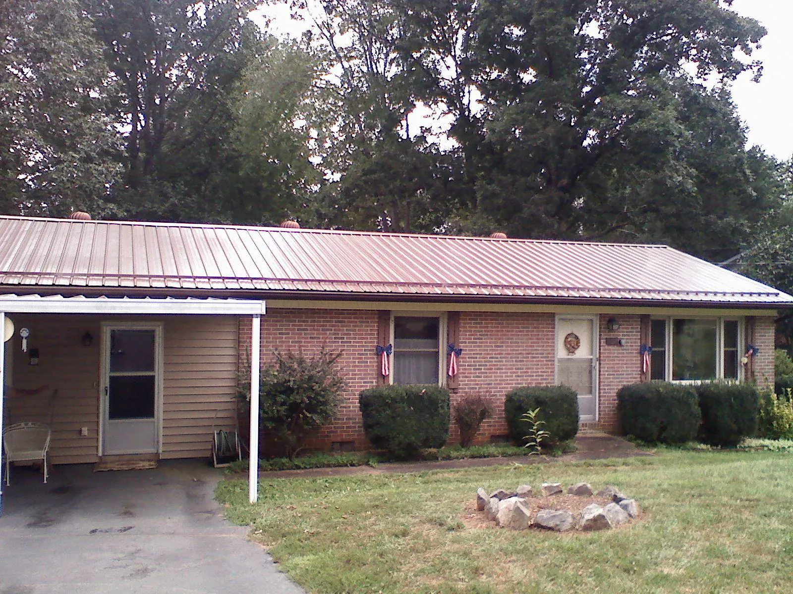 Bronze metal roof and carport on a brick ranch home — Roof Repair work by our crew in Hanley Falls