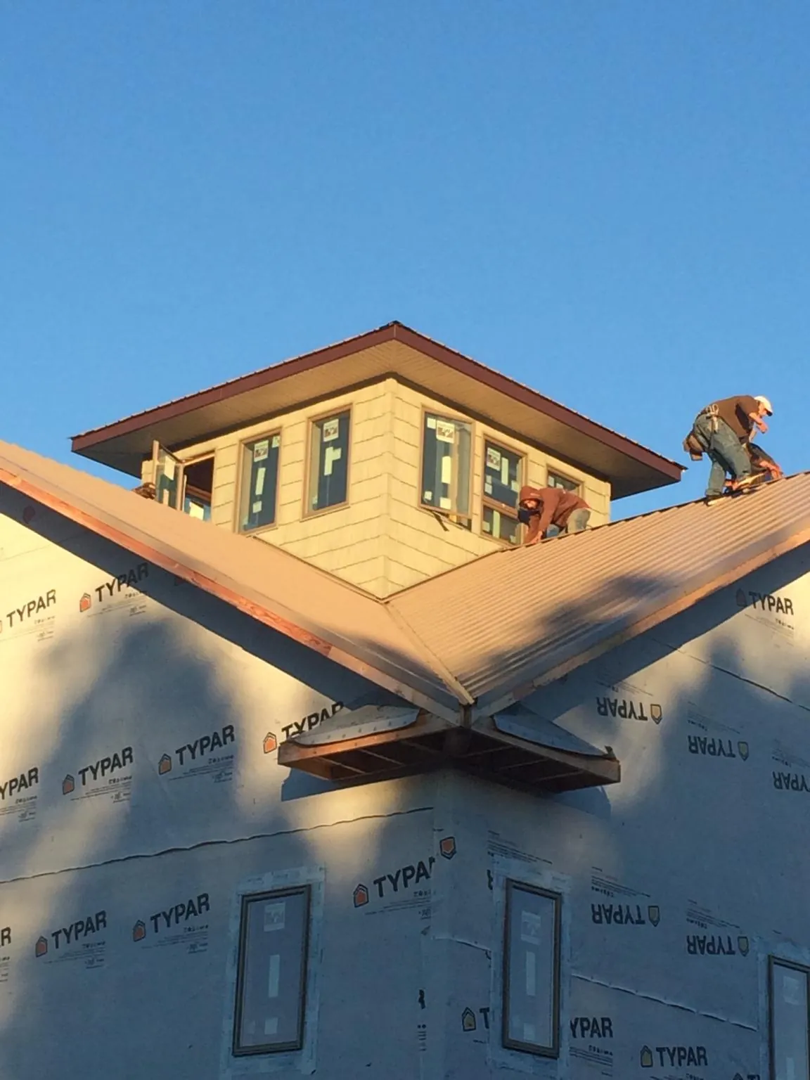 Roofers working around a rooftop cupola on a new metal roof at sunset — Roof Waterproofing in Hanley Falls by Roofing Brothers